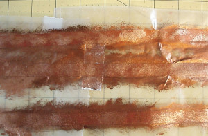 Place the three pieces of Red Artist Tape on wax paper and sponge paint it with copper paint.